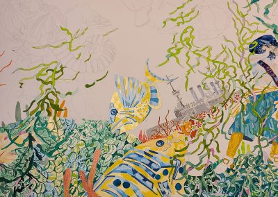 A close up of the painting that includes the left side of the Pirate, the battleship and two fishes. The large fish is painted in a yellow gold and blue. The smaller fish is painted in light yellow and blue. The battelship is painted in tones of taupe and gray. You can see the merimades tail and it is painted in shades of blue, green and yellow. The seaweed is painted in tones of a yellow green, dark green, blue and pink.